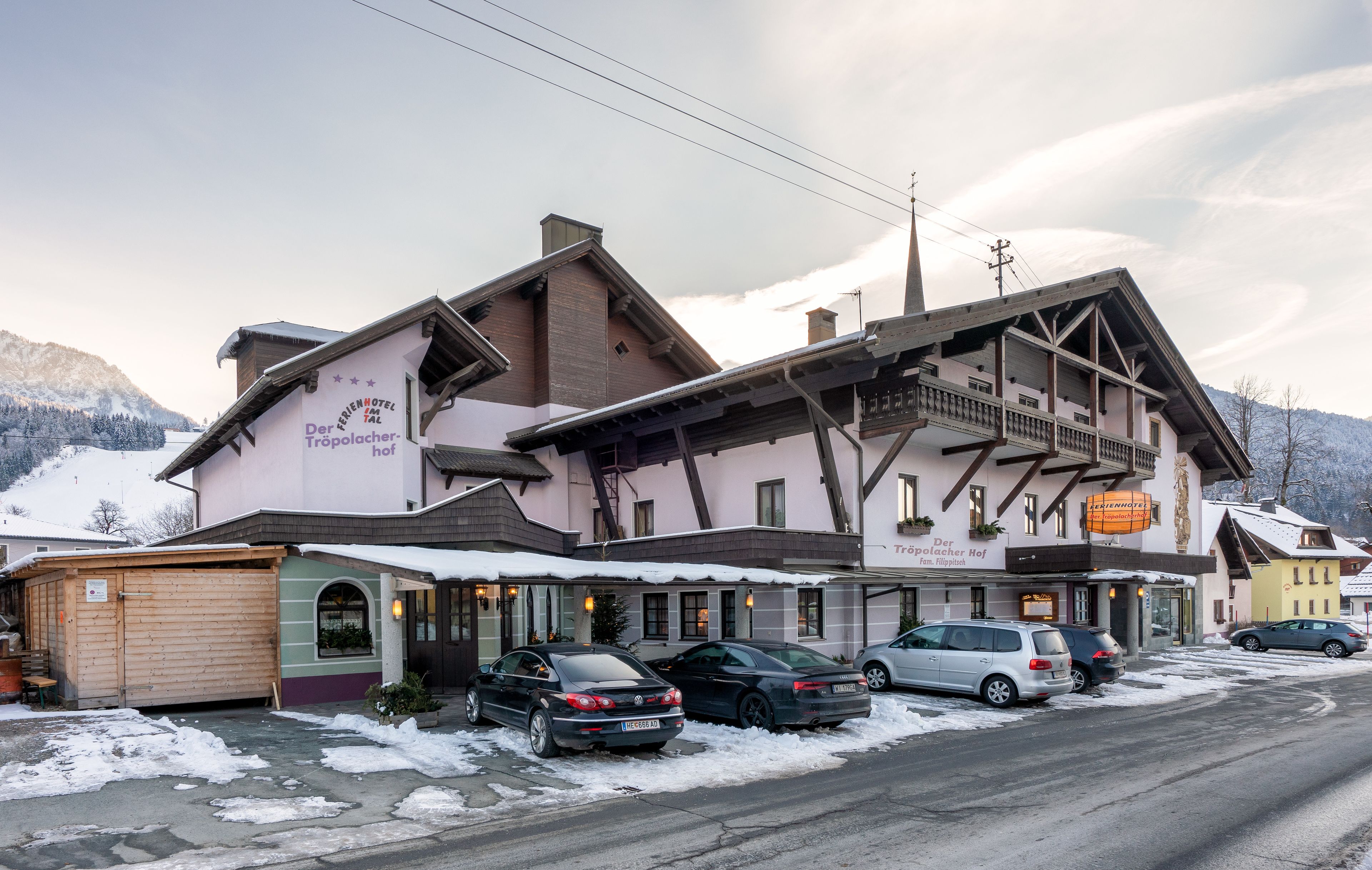 A hotel with a traditional Alpine architectural style, featuring a balcony and a sign indicating it is a Tröpolacherhof.