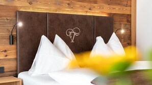 Een moderne slaapkamer met een bruin hoofdeinde, witte kussens en een nachtkastje met een lamp.