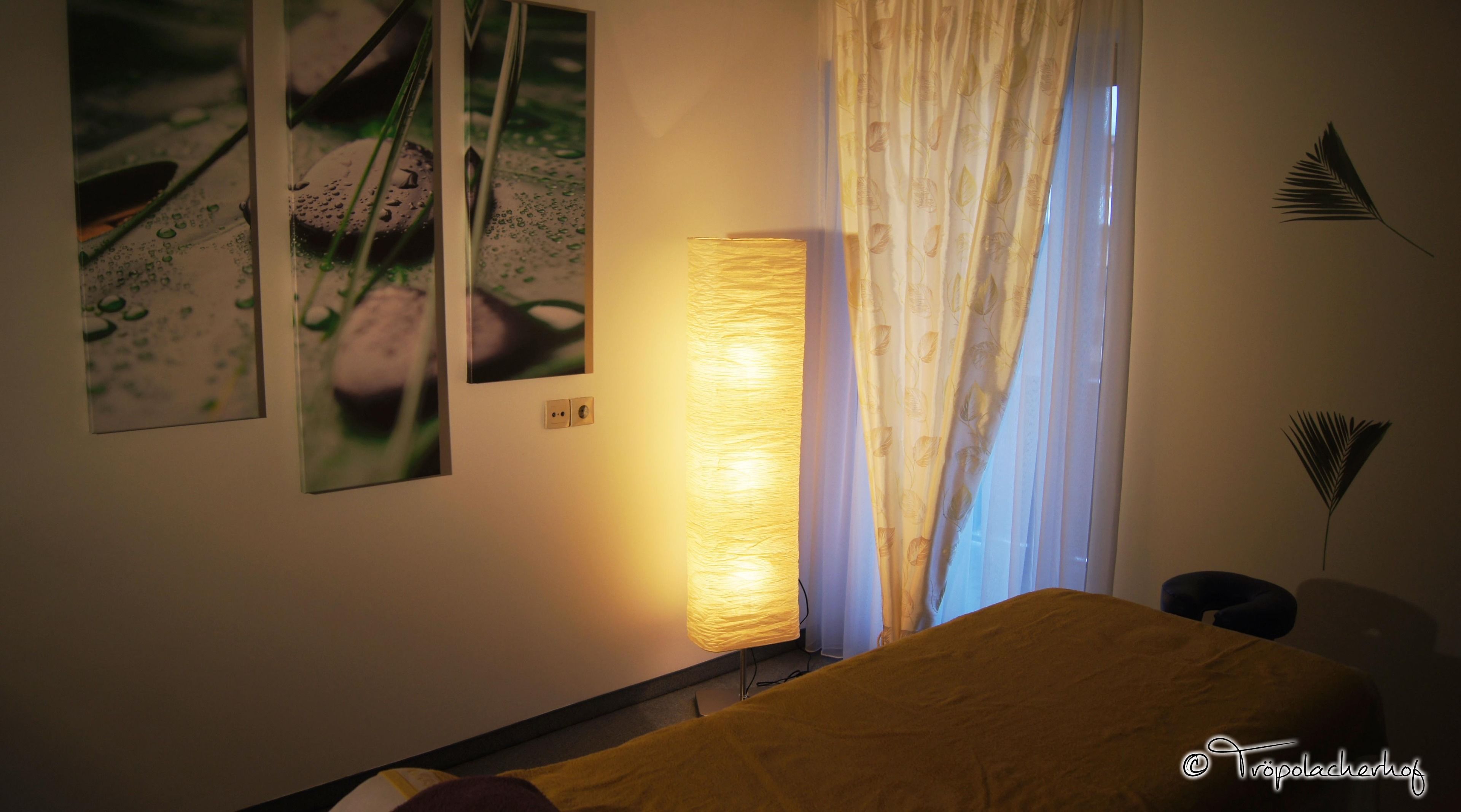 A hotel room with a bed, a wall-mounted lamp, and two framed pictures.