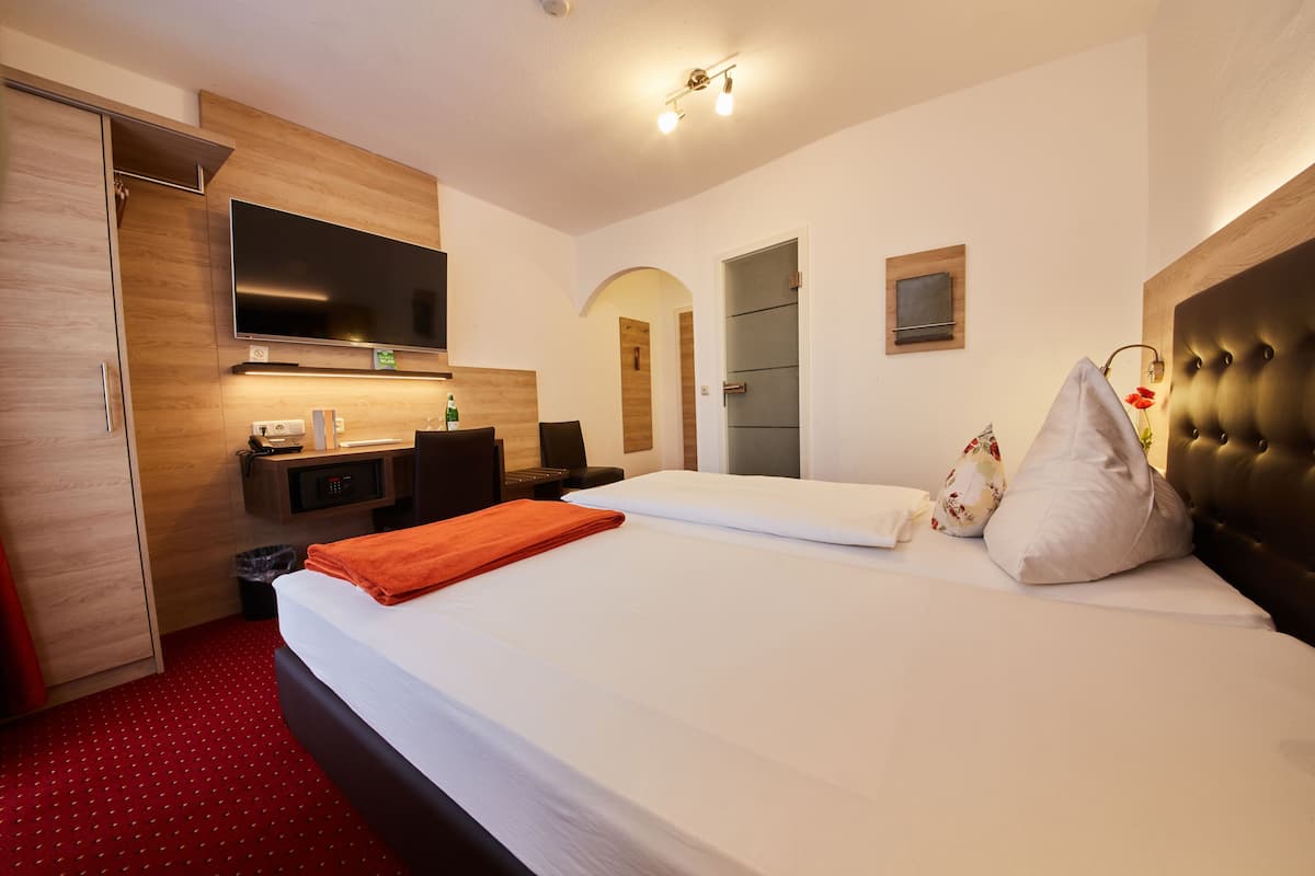 A hotel room with a bed, a desk, a TV, and a wardrobe.