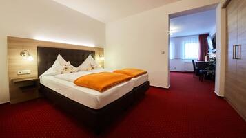 A hotel room with a large bed, two pillows, a nightstand, and a red carpet.