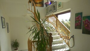 A staircase with wooden railings and marble steps, surrounded by potted plants and framed artwork on the walls. - Hotel Schoos (Fleringen)