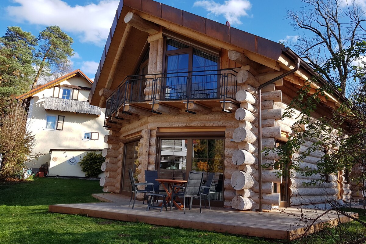Une cabane en rondins dotée d’un balcon et d’un patio aménagé avec des meubles d’extérieur.