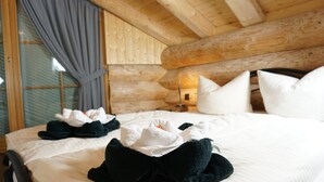 A cozy log cabin room with a bed, pillows, and a bedside table.