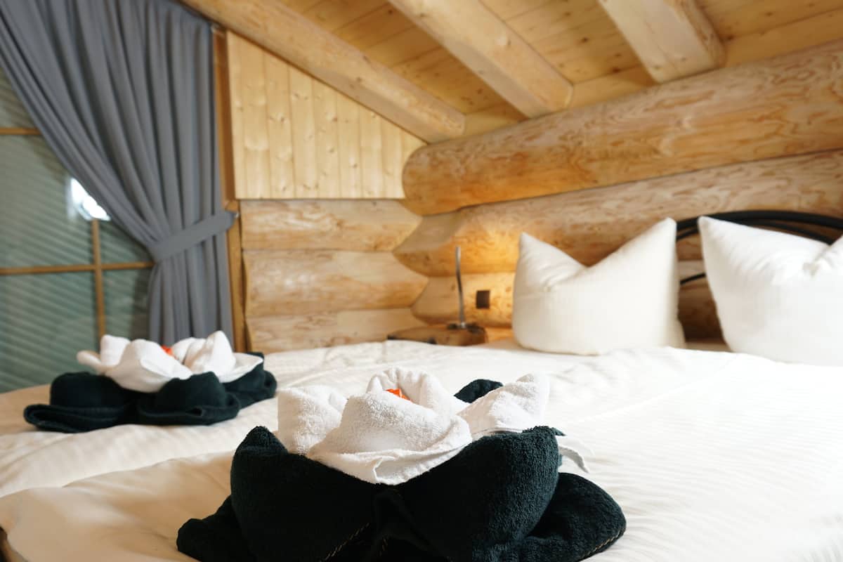 A cozy log cabin room with a bed, pillows, and a bedside table.