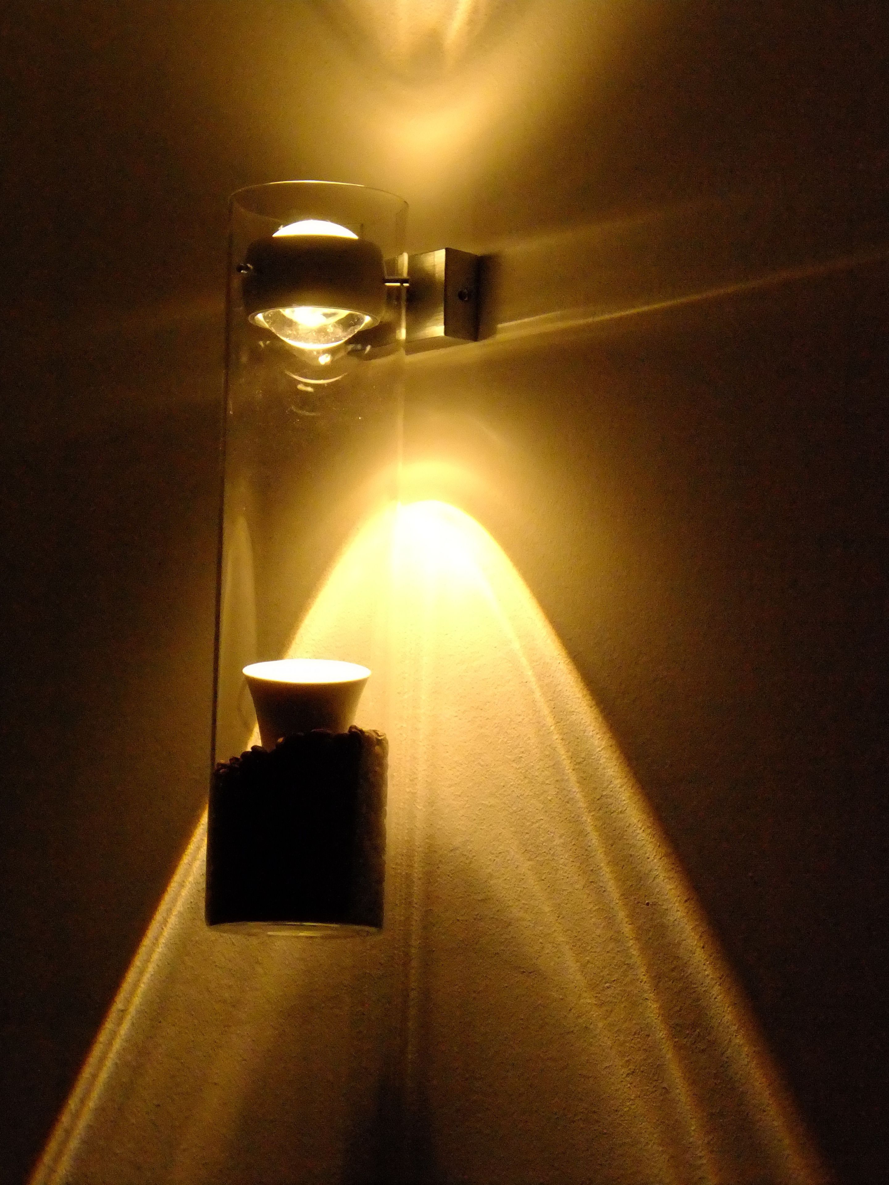 A wall-mounted light fixture with a glass enclosure and a visible bulb.