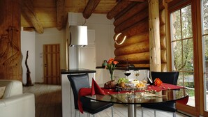A wooden cabin interior with a dining table set for a meal, surrounded by chairs.
