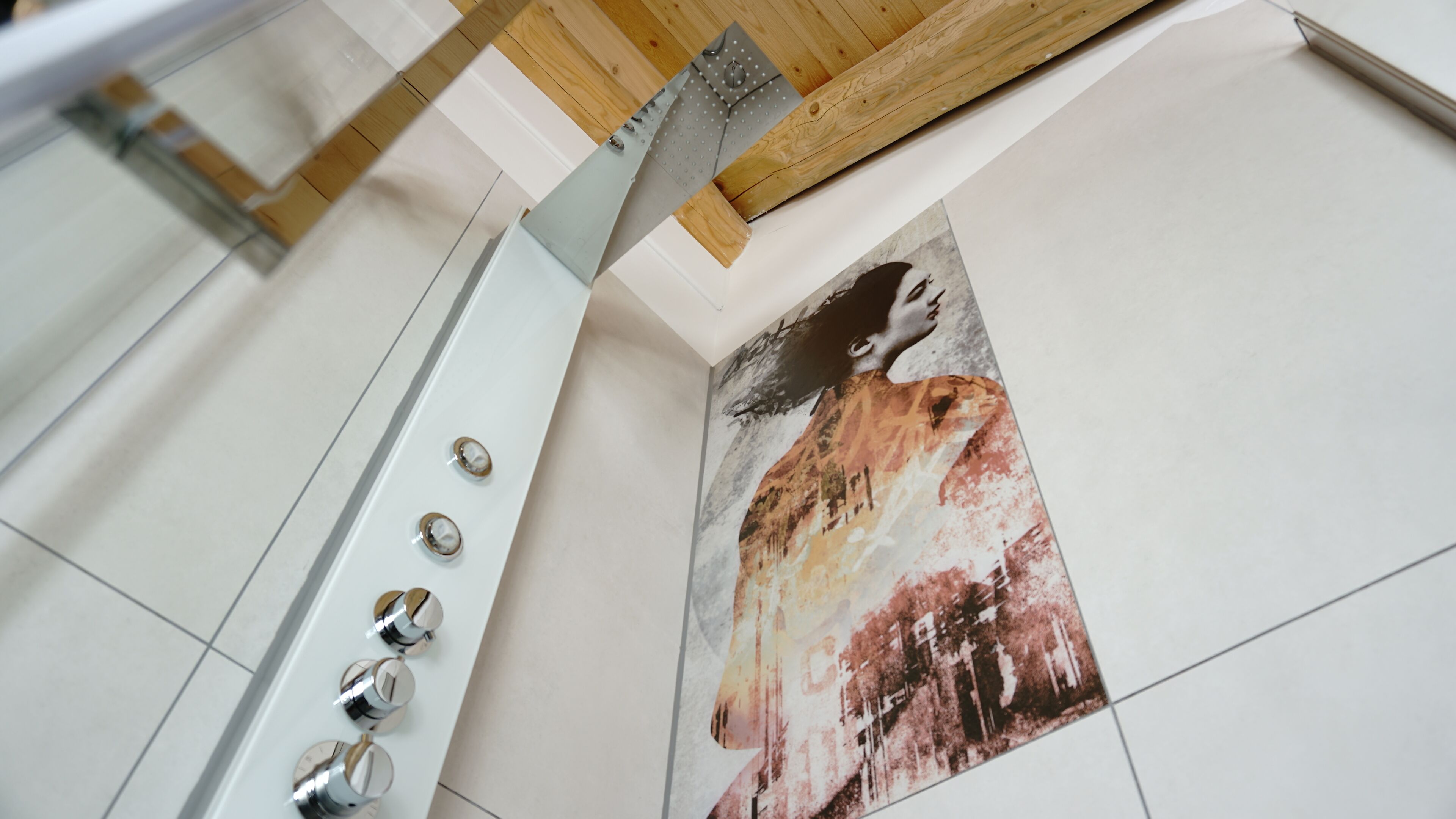Un baño con piso de baldosas blancas, techo de madera y un perchero de toallas en la pared con un cuadro abstracto grande.