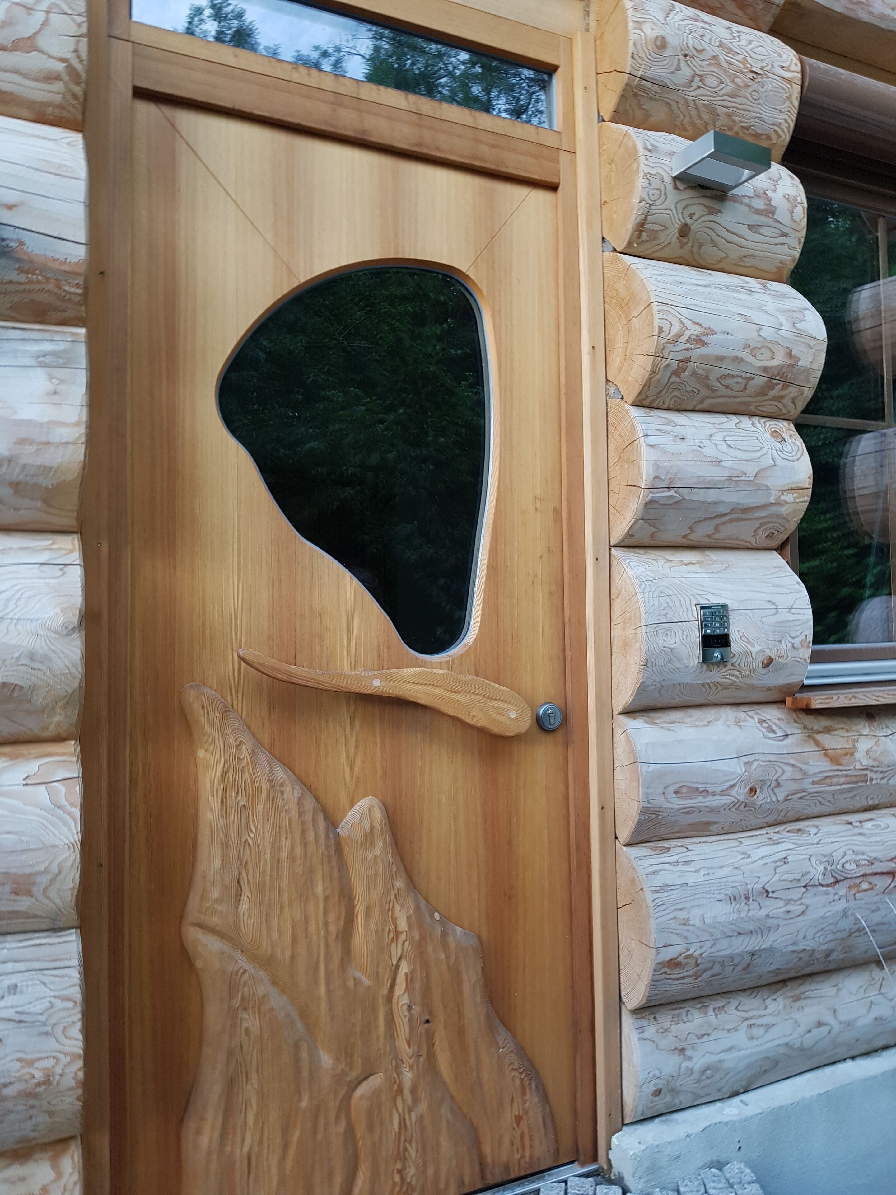 Un plafond en bois doté d’un décor original, comprenant un élément sculpté qui ressemble à une branche d’arbre et un objet noir de forme ovale.