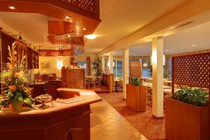 A hotel reception area with a wooden reception desk, a reception sign, and a dining area with tables and chairs. - Hotel Montana Lauenau (Lauenau)