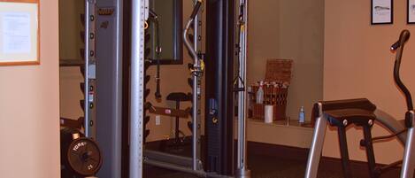 A gym with a weight machine, a treadmill, and a wall-mounted exercise bike.