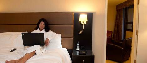 A hotel room with a bed, a nightstand with a lamp, a chair, and a door.