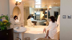 A hotel bathroom with a large mirror, a sink, and a bathtub.