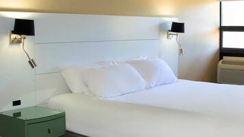 A hotel room with a large bed, two bedside tables, and wall-mounted lamps.