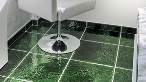 Une salle de bain moderne avec un meuble-lavabo blanc, une serviette verte et une vue sur la mer par une fenêtre.