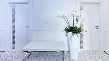 A room with a white reception desk, a white vase with flowers, and a patterned floor.