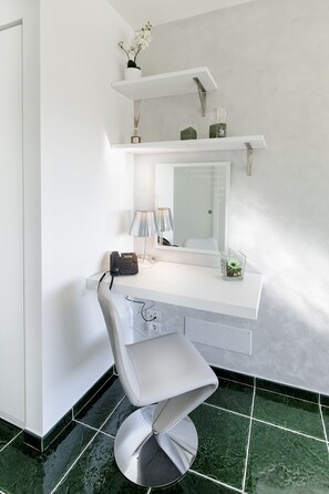 Un baño moderno con un tocador blanco, un espejo grande y una silla blanca.