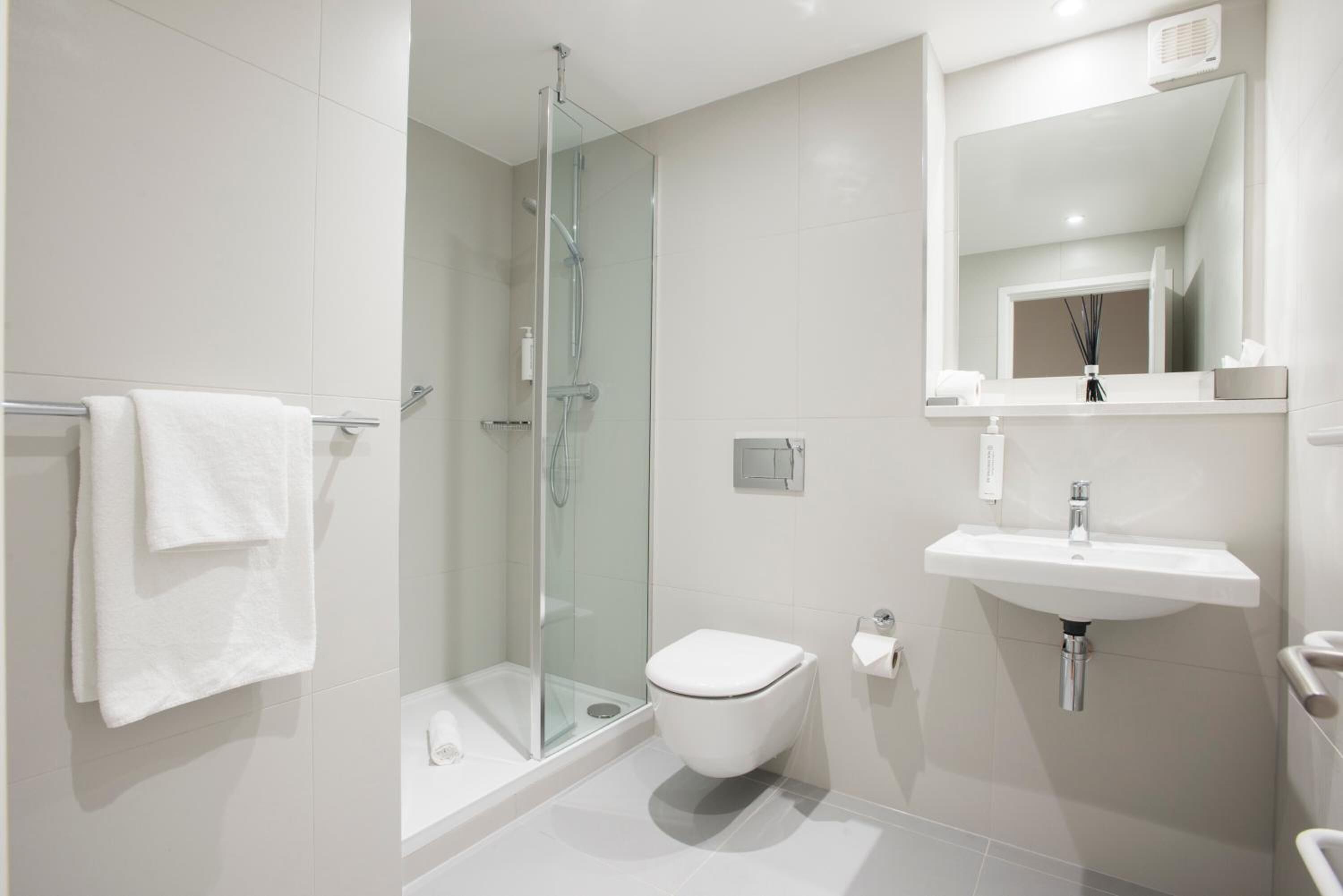 Un bagno moderno con cabina doccia in vetro, un water bianco e un lavabo con specchio sopra.