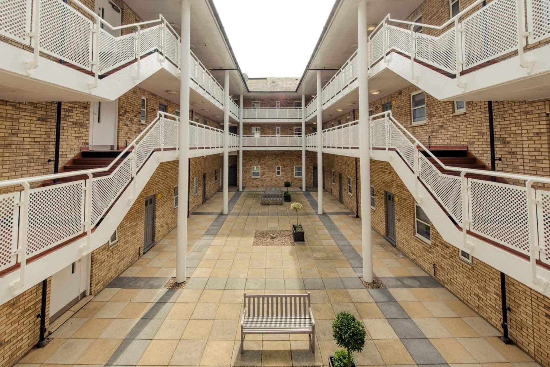 Un atrium à plusieurs niveaux, doté d’un espace central aménagé en salon, de rampes blanches et de murs en briques.
