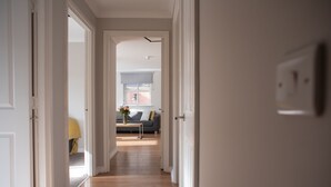 A hallway with wooden flooring leading to a living area with a sofa and a table. - PREMIER SUITES Reading (Reading)