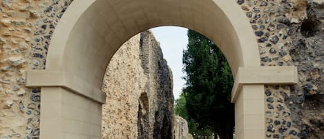 Un sendero de piedra arqueado que conduce a un edificio histórico con ruinas visibles.