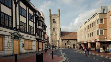 A street with historic buildings, a church tower, and pedestrians.