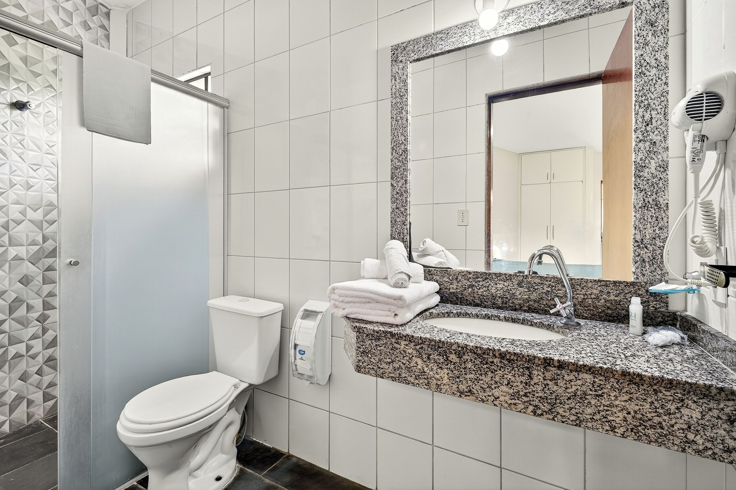 Un baño con inodoro, lavamanos y espejo.