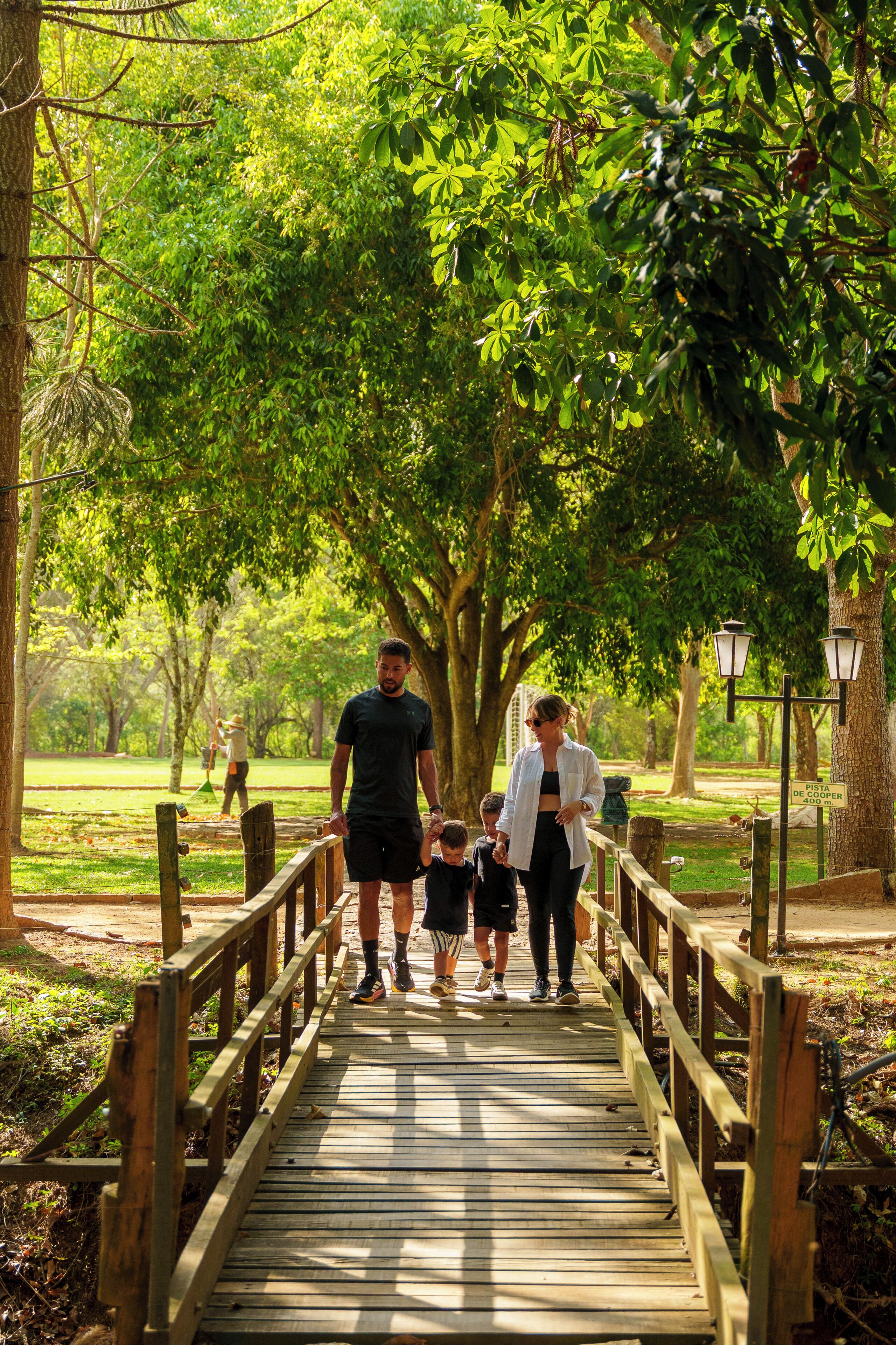 A wooden bridge in a park with people walking.
