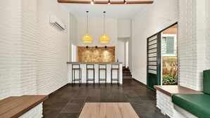 Une cuisine moderne avec des murs en briques blanches, un îlot central, des tabourets de bar et des luminaires suspendus.