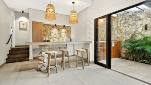 Une cuisine moderne avec un mur de crédence en pierre, des tabourets en bois et des luminaires suspendus.
