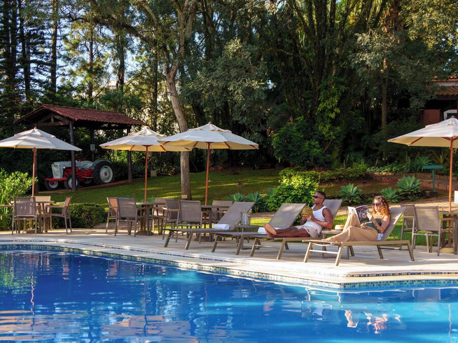 Una piscina techada, una piscina al aire libre, sombrillas