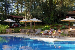 Una piscina techada, una piscina al aire libre, sombrillas