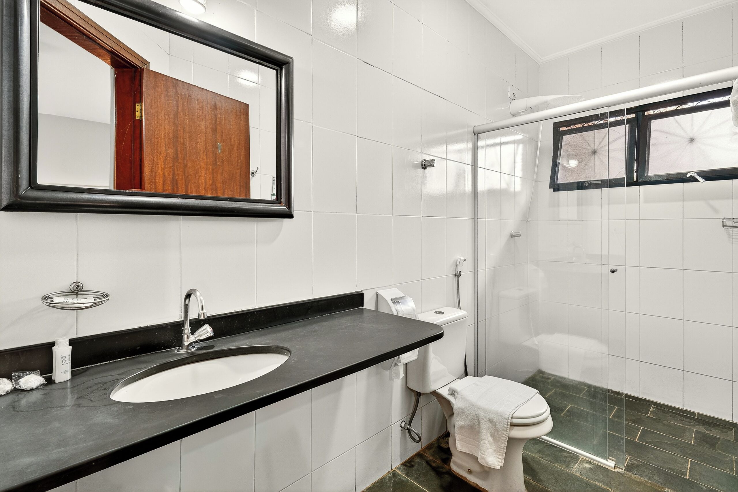 A bathroom with a sink, mirror, toilet, and shower.