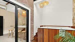 Une salle de bain moderne avec une baignoire en bois, une cabine de douche en verre et un escalier menant à un deuxième étage.