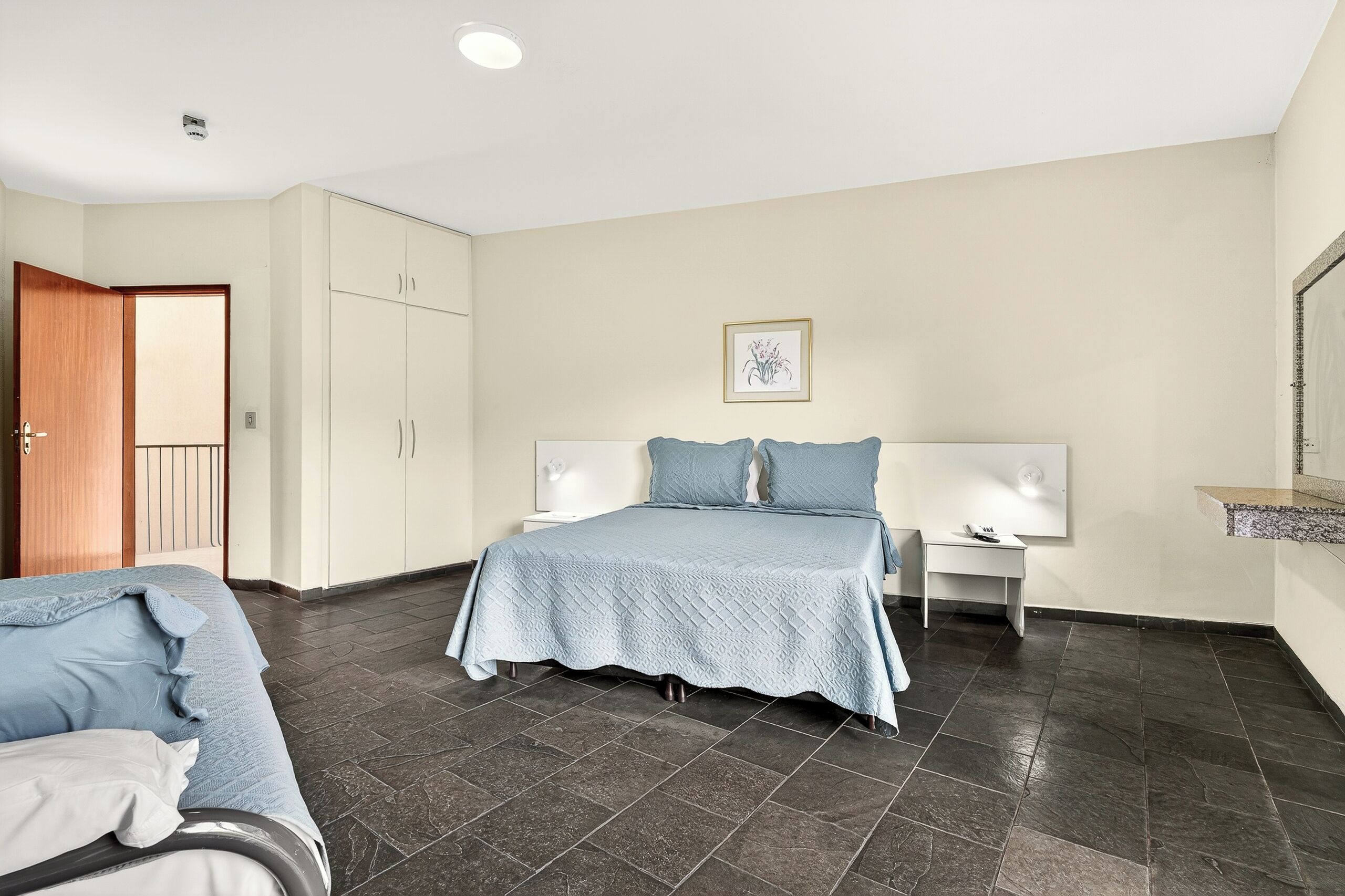 A bedroom with a bed, a bedside table, a wardrobe, and a door.