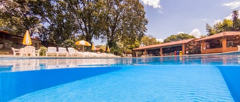 Una piscina techada, una piscina al aire libre, sombrillas