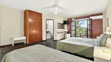 A bedroom with two beds, a TV, a ceiling fan, and a view of the outdoors.