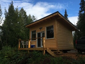 A small wooden cabin with a deck, a sliding door, and a small porch area.