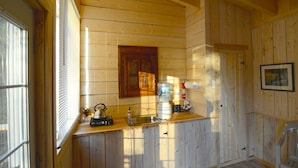 Interior de uma cabana de madeira com cozinha, incluindo pia, chaleira e cafeteira.