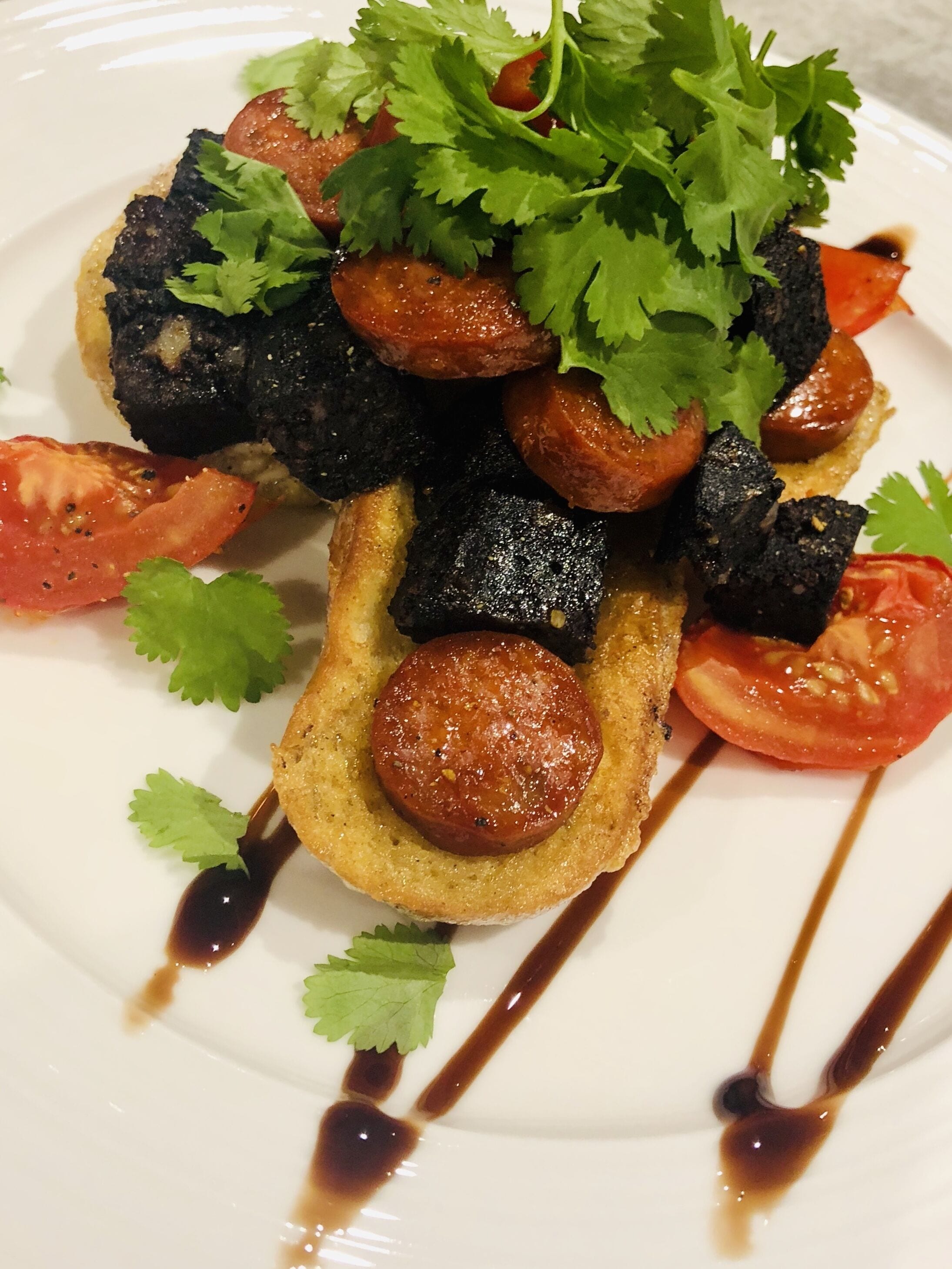 Une assiette de nourriture comprenant du pain, des tomates et une sauce foncée.