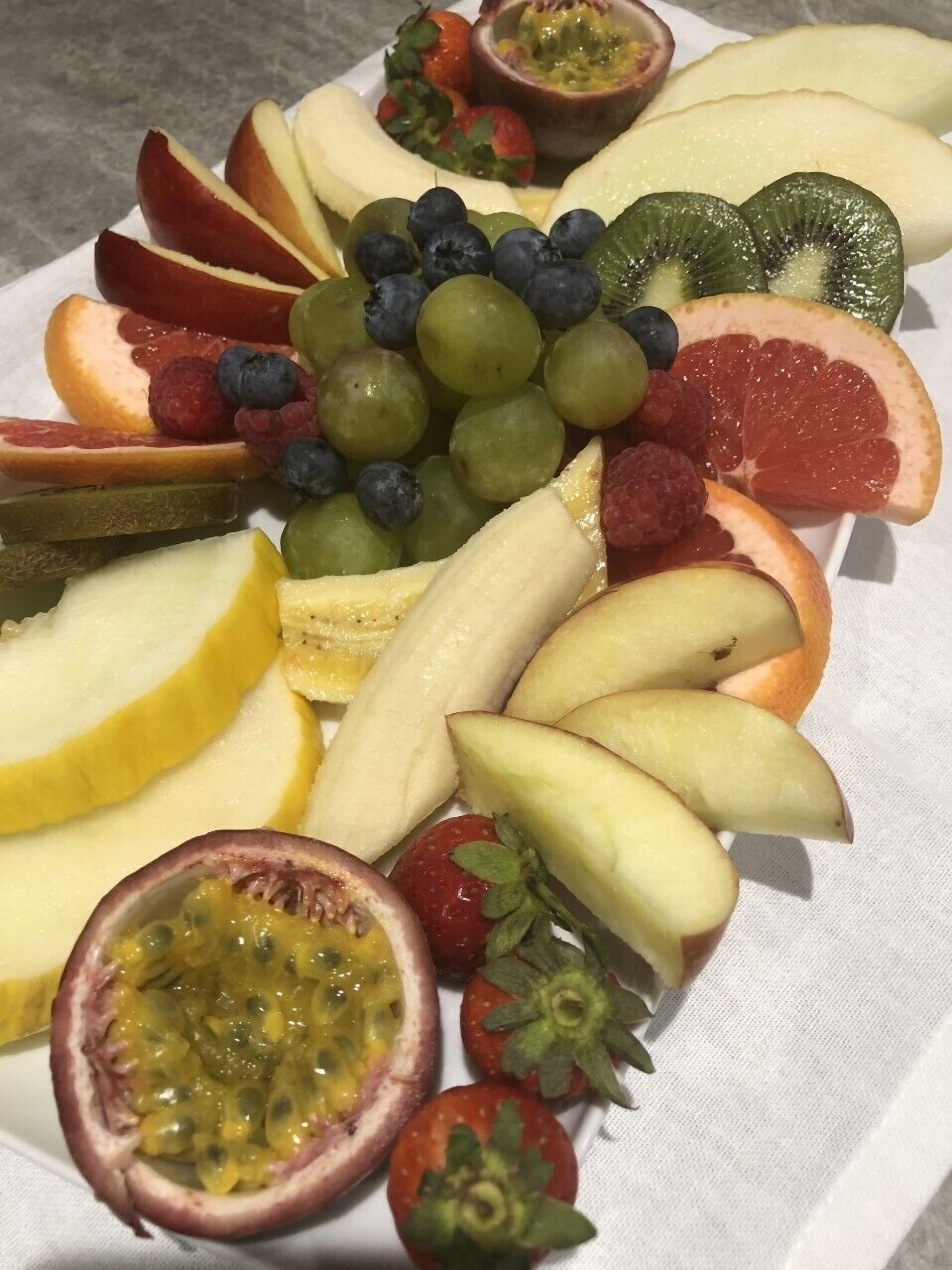 A fruit platter with various fruits including apples, bananas, grapes, and strawberries.