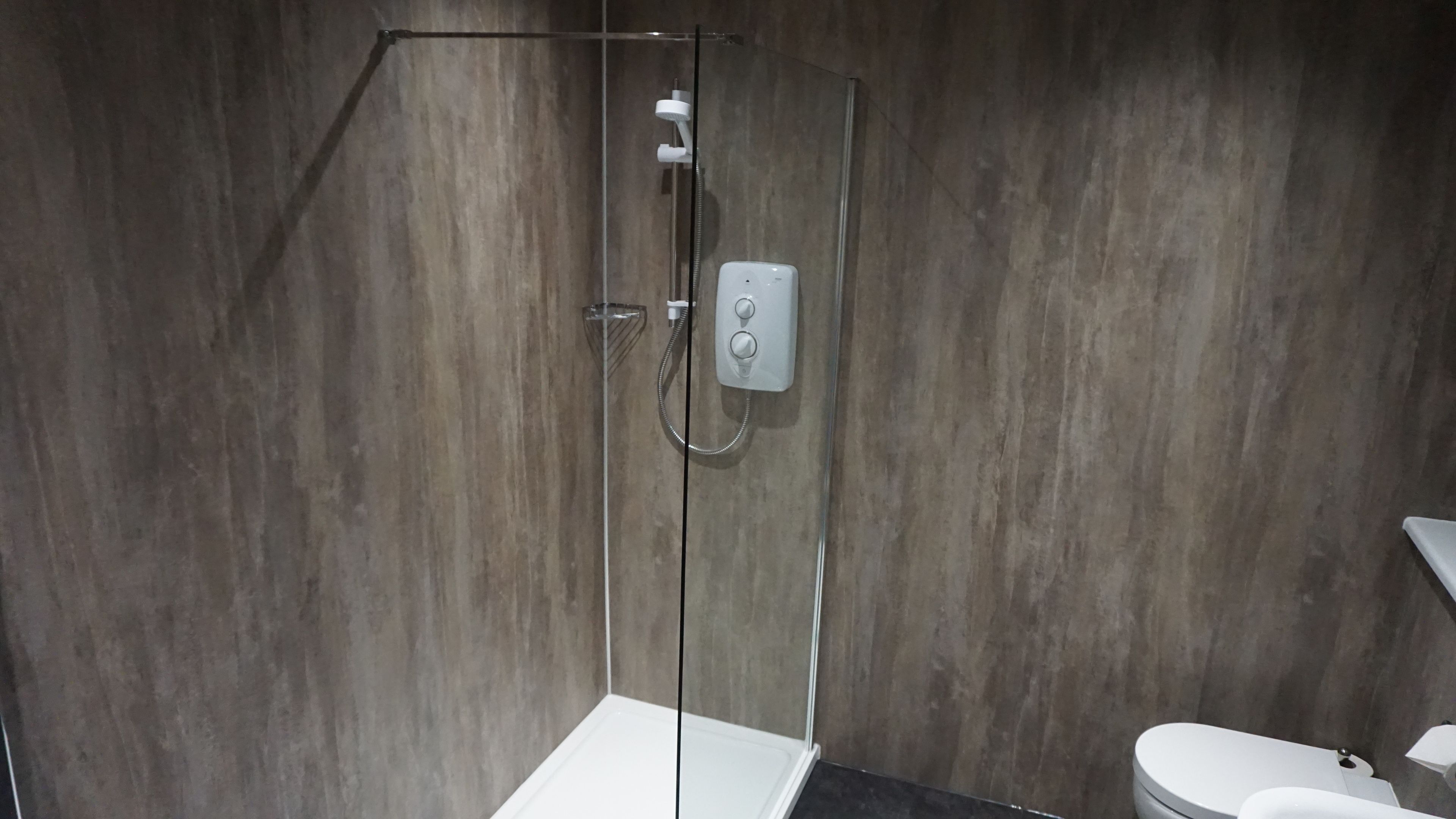 A modern bathroom with a glass-enclosed shower, a white toilet, and a dark countertop.