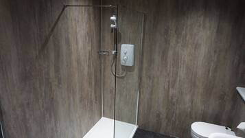 A modern bathroom with a glass-enclosed shower, a white toilet, and a dark countertop.