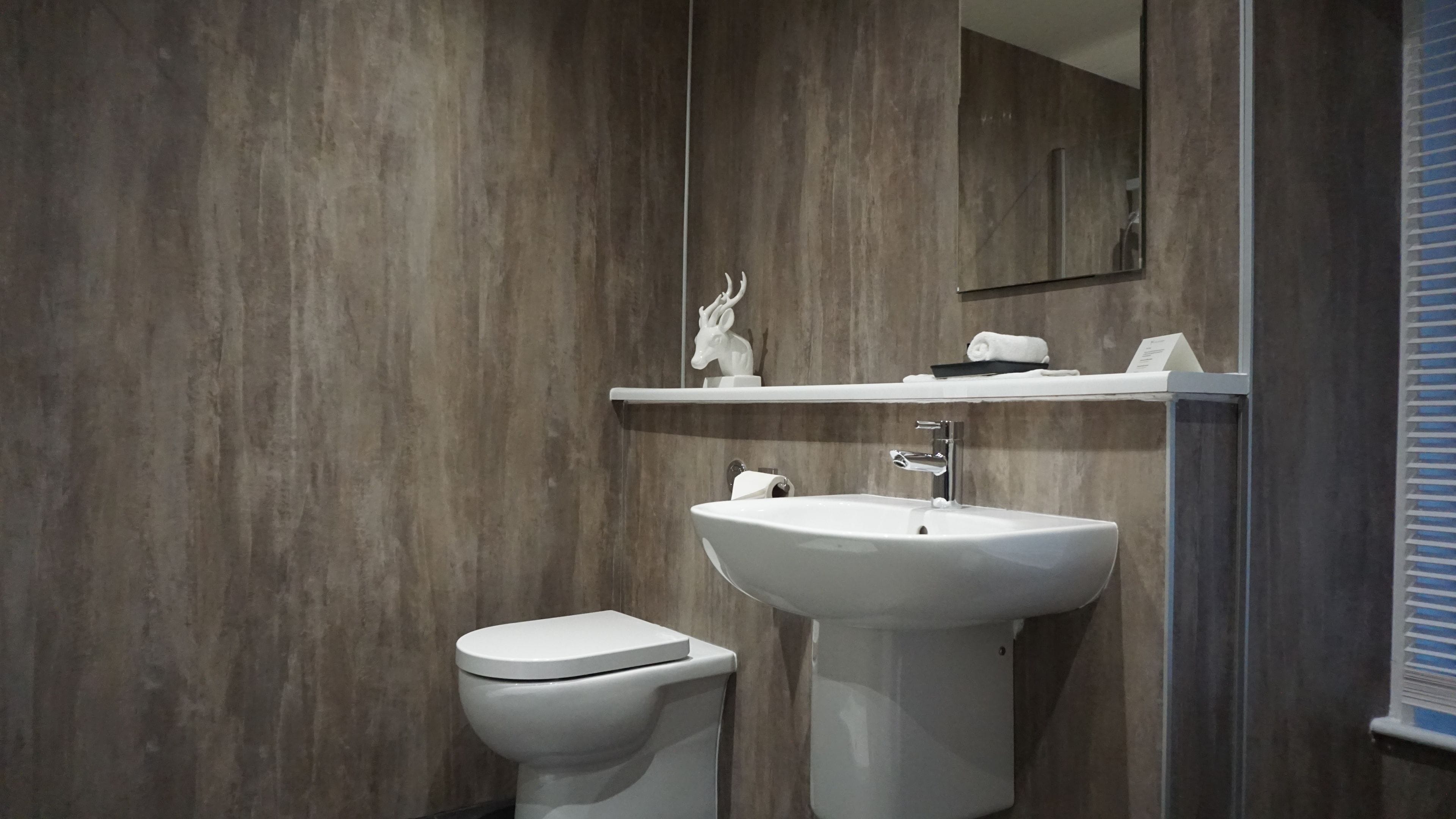 Un baño moderno con pared de madera, un inodoro blanco y un lavamanos blanco con un espejo encima.