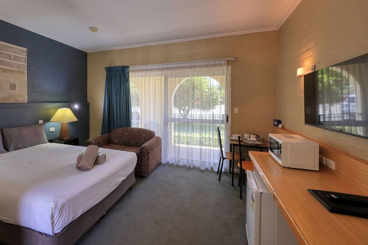Ein Hotelzimmer mit einem Bett, einem Schlafsofa, einem Esstisch, einer Mikrowelle und einem Fernseher.