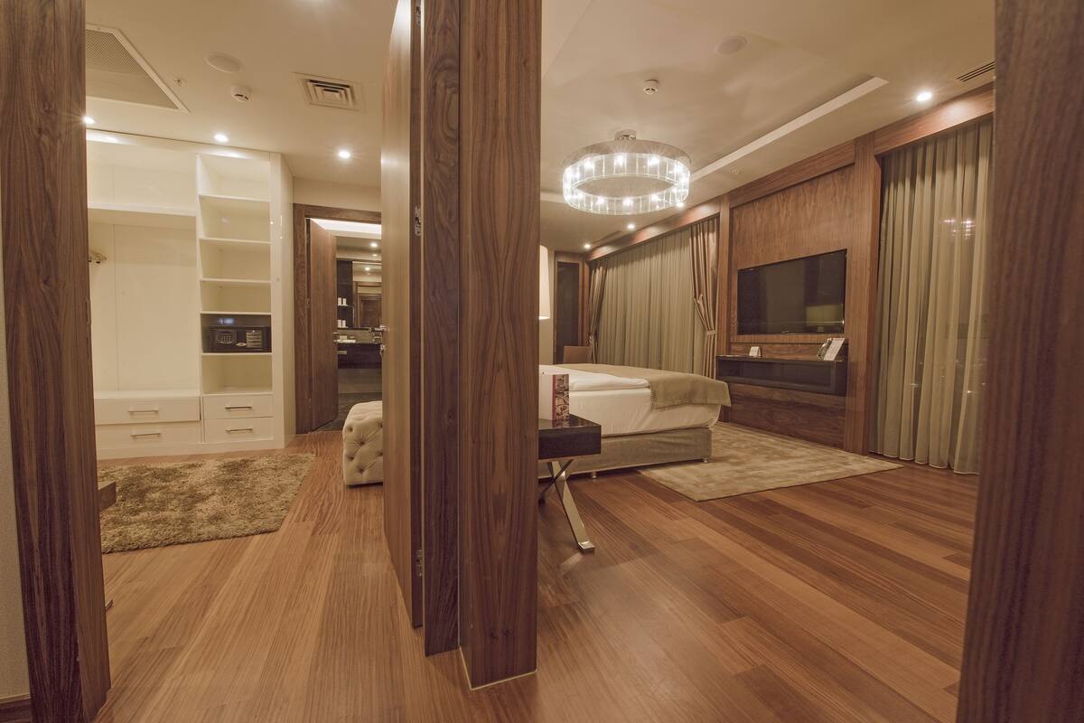 Une chambre moderne avec un plancher en bois, un grand lit, une télévision et un dressing.