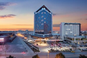 Un hotel moderno con una fachada de vidrio destacada, un centro de convenciones y un estacionamiento.