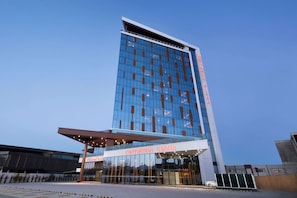 Welcome to the DRAMADA PLAZA Convention Center, featuring a striking glass facade and covered entrance.