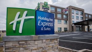 Une enseigne Holiday Inn Express & Suites, avec un socle en pierre, devant un bâtiment doté de nombreuses fenêtres et arborant le drapeau américain.