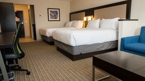 Ein Hotelzimmer mit zwei Betten, einem Schreibtisch, einem Sessel und Teppichboden.